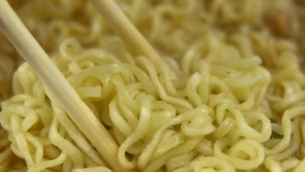 Le tagliatelle istantanee sono mescolate con bacchette cinesi. Prodotto giallo ramen primo piano — Video Stock