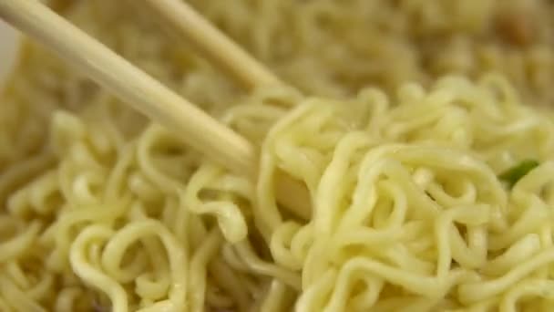 Les nouilles instantanées sont mélangées avec des baguettes chinoises. Ramen jaune brassé gros plan — Video