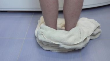 Bir adam banyo havlusunu yere atar ve küvete tırmanır. Bacakların Arka Görünümü