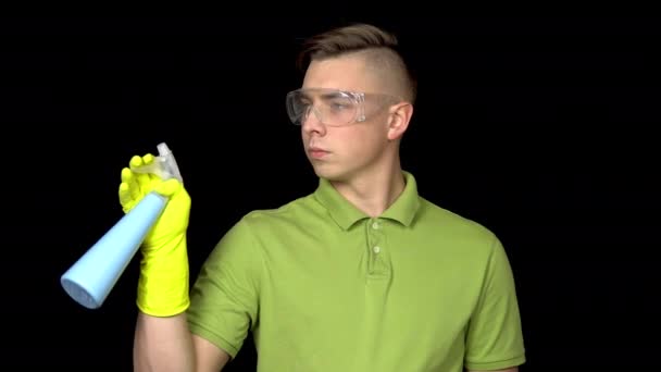 A young man shoots out of a spray of water, like a gun. A man in safety glasses and gloves for cleaning. On a black background — Stock Video