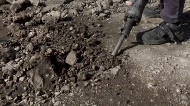 Kaya matkabıyla çalışan bir adam. Bir kaya matkabı asfaltı kırar. Büyük ve ağır yol onarım aracı