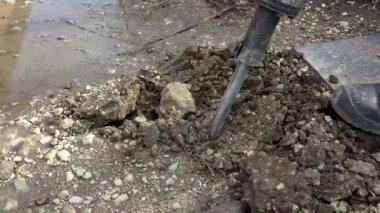 Kaya matkabıyla çalışan bir adam. Bir kaya matkabı asfaltı kırar. Büyük ve ağır yol onarım aracı