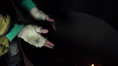 Evsiz bir adam geceleri bir ateş fıçısının yanında ellerini ısıtır. Eller yukarı..