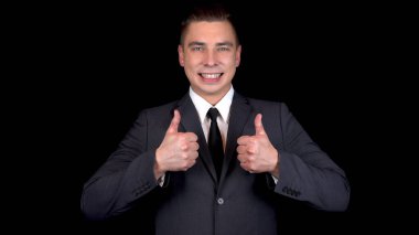 Genç iş adamı iki eliyle birden ortaya çıkar. Siyah arka planda siyah takım elbiseli adam.