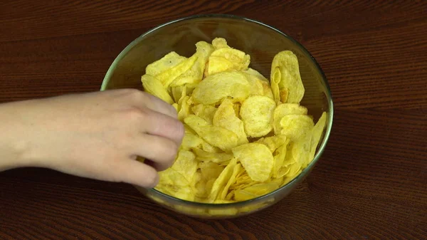 Die Hände von Menschen, die aktiv Chips aus einer großen Schüssel nehmen. Die Gesellschaft von Freunden isst Kartoffelchips. Hände aus nächster Nähe. Hungrige Menschen — Stockfoto