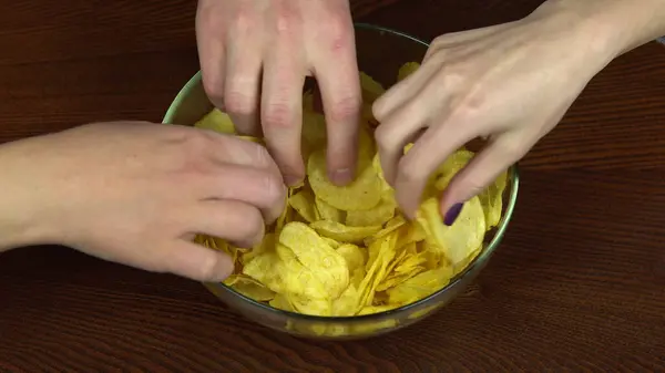 큰 접시에서 감자칩을 꺼내는 사람들이 있습니다. 친구들 과 함께 감자칩을 먹는다. 손을 감아 — 스톡 사진