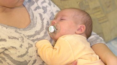 Genç anne bebeğini kollarında uyutuyor. Bebeği emzirirken anne kollarında uzanıyor..