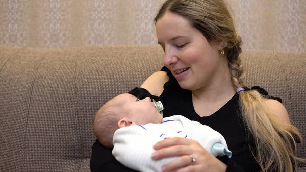 Baby in the arms of mom. Young mother puts to sleep on the hands of a nursing baby. Face close up — Stock Photo, Image