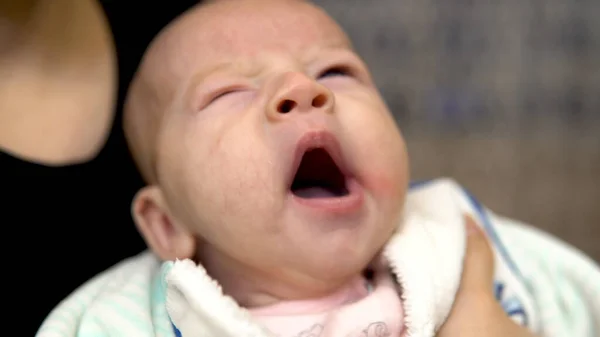 Baby in the arms of her mother. The baby is yawning. Face close up — Stock Photo, Image