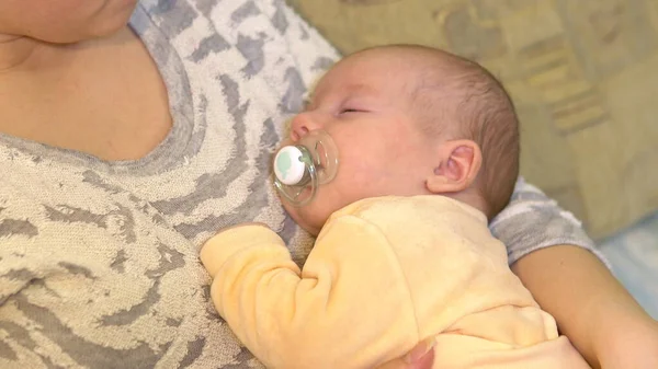 Genç anne bebeğini kollarında uyutuyor. Bebeği emzirirken anne kollarında uzanıyor..