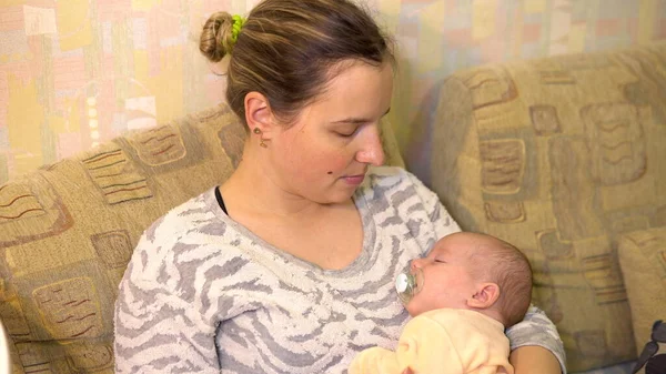 Young mother puts her baby to sleep in her arms. Breastfeeding Baby lies with mom in her arms close-up — Stock Photo, Image