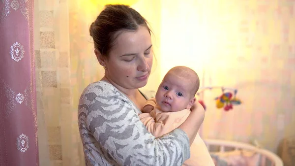 Een jonge moeder houdt een baby in haar armen. De baby lacht. — Stockfoto