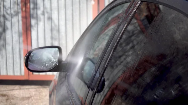 Un hombre lava la tierra de un coche con un chorro de agua de alta presión. Detergente especial para lavado de autos. Lava un coche delante de la casa . — Foto de Stock