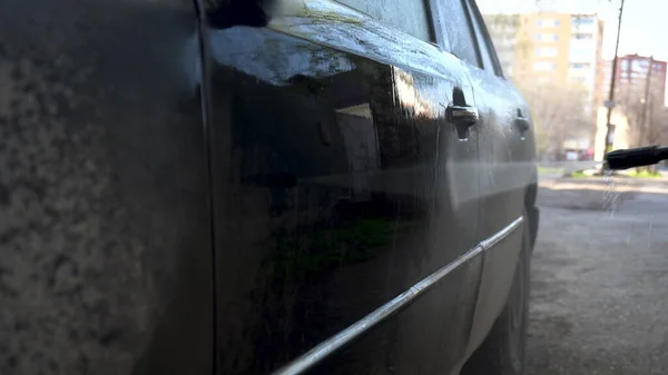 Lava la suciedad de un coche con un primer plano de chorro de agua a alta presión. Detergente especial para lavado de autos. Lava un coche delante de la casa . —  Fotos de Stock