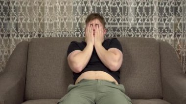 Genç bir adam kanepede oturur ve şişman bir göbeğe şaplak atar. Karantinada fazla kilo almış..