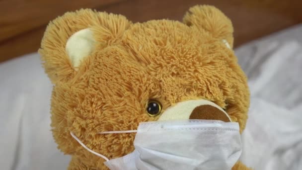 Το αρκουδάκι μετράει τη θερμοκρασία με το χέρι. Ο γιατρός κάνει μια μέτρηση της θερμοκρασίας εφαρμόζοντας ένα χέρι στο μέτωπό του. Η αρκούδα ξαπλώνει στο κρεβάτι με μια ιατρική μάσκα. — Αρχείο Βίντεο