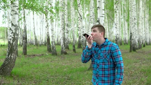 Молодой человек ищет сотовую сеть в березовом лесу. Мужчина разговаривает по телефону, но связь прерывается. Мужчина нервничает. . — стоковое фото