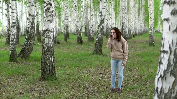 Młoda kobieta szuka sieci komórkowej w lesie brzozowym. Dziewczyna rozmawia przez telefon, ale połączenie jest przerwane. Kobieta jest zdenerwowana.. — Zdjęcie stockowe