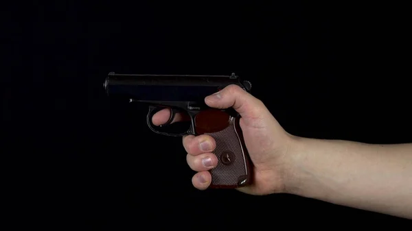 Ένας άντρας πυροβολεί από ένα πιστόλι. Το πιστόλι στο χέρι κάνει ένα σουτ. Σε μαύρο φόντο — Φωτογραφία Αρχείου