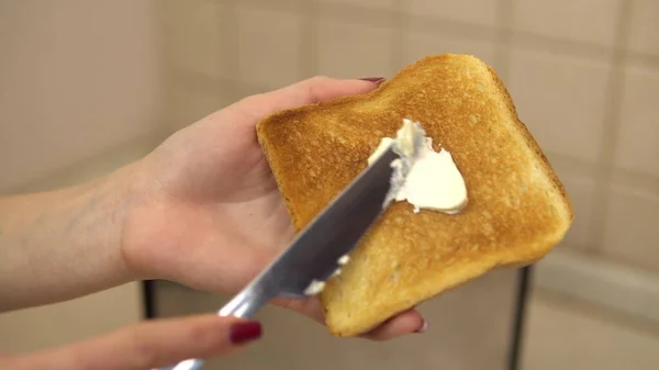 La donna spalma il burro sul pane tostato. Il burro si spalma sul pane. Cibo per colazione — Foto Stock