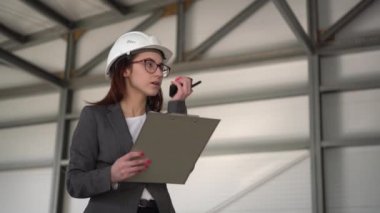 Kasklı ve belgeli genç bir kadın inşaat alanında telsizle konuşuyor. Takım elbiseli patron kadın mimari belgelerinin kaydını tutuyor. Bir kız etrafına bakıyor..