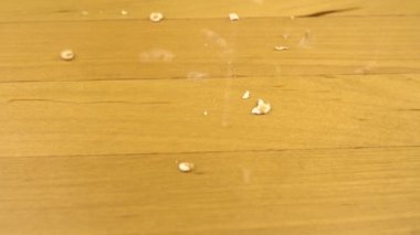 Herkül taneleri ahşap bir yüzeye düşer. Makro boy yulaf ezmesi. Yavaş çekim.