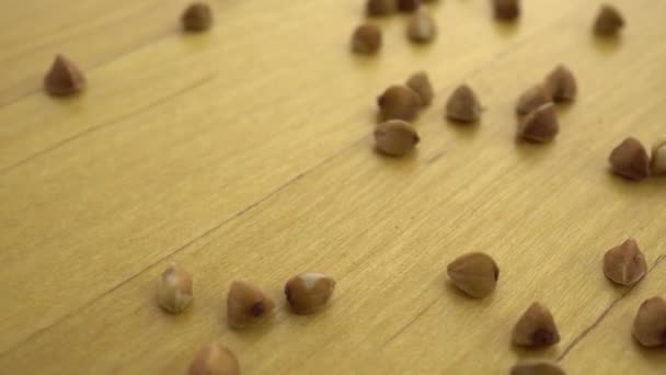 Grañones de trigo sarraceno sobre una superficie de madera. Plataforma móvil con trigo sarraceno . — Vídeos de Stock