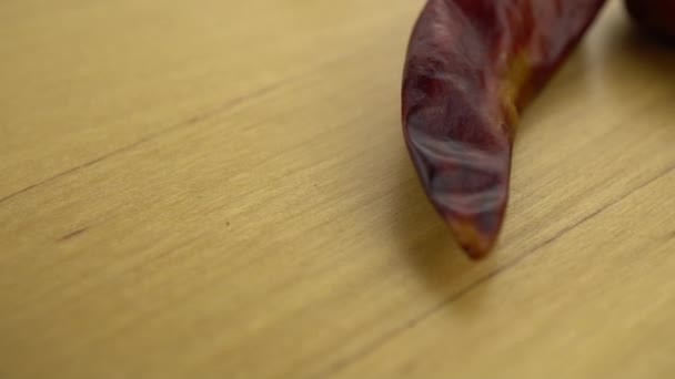 Peperoncini di peperoncino che cadono su una superficie di legno. Macro shot di peperoncino rosso. Rallentatore. — Video Stock