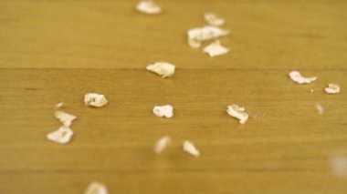 Herkül taneleri ahşap bir yüzeye düşer. Makro boy yulaf ezmesi. Yavaş çekim.