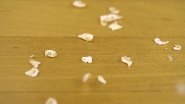 Hercules flakes fall on a wooden surface. Macro shot of oatmeal. Slow motion. — Stock Video
