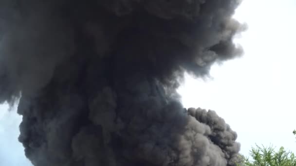 Schwarzer Rauch steigt in den Himmel. Ein großer Chemiebrand in einem Fabrikgebäude. Dichter schwarzer Rauch bedeckt den Himmel. — Stockvideo