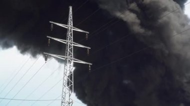 Bir elektrik kulesi siyah dumandan oluşan bir arka planda duruyor. Fabrika binasında büyük bir kimyasal yangın. Yoğun siyah duman gökyüzünü kaplıyor..