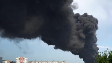 Binaların üzerinden siyah duman yükseliyor. Fabrika binasında büyük bir kimyasal yangın. Yoğun siyah duman gökyüzünü kaplıyor..
