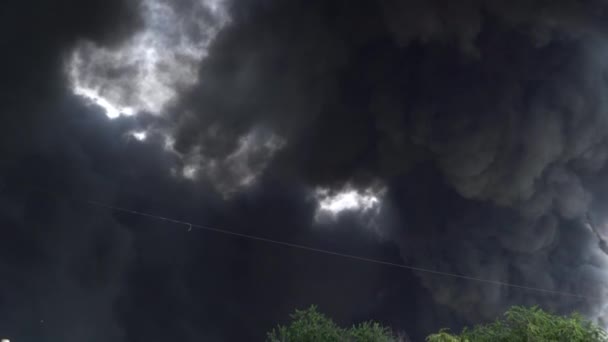 Zwarte rook stijgt de lucht in. Een grote chemische brand in een fabrieksgebouw. Dikke zwarte rook bedekt de lucht. — Stockvideo