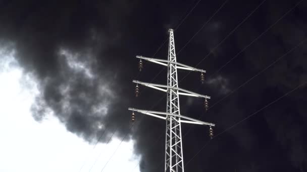 Uma torre elétrica fica contra um fundo de fumaça preta. Um grande incêndio químico num edifício de fábrica. A fumaça preta grossa cobre o céu. — Vídeo de Stock