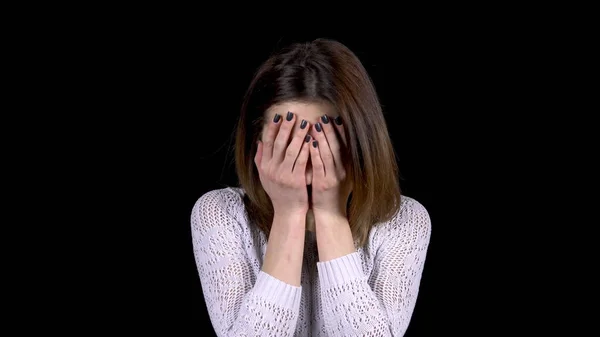 Tânăra își arată emoțiile de tristețe pe față. Femeia plânge și își acoperă fața cu mâinile pe un fundal negru . — Fotografie, imagine de stoc
