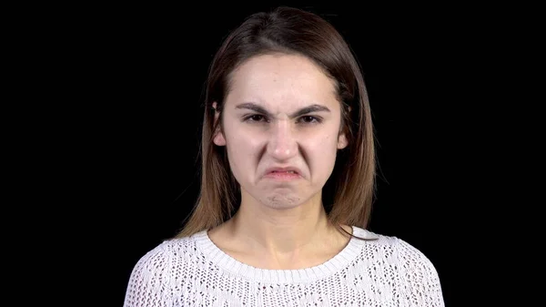 Una mujer joven muestra emociones de asco en su cara. Mujer contornea su cara de la abominación en un fondo negro primer plano . —  Fotos de Stock