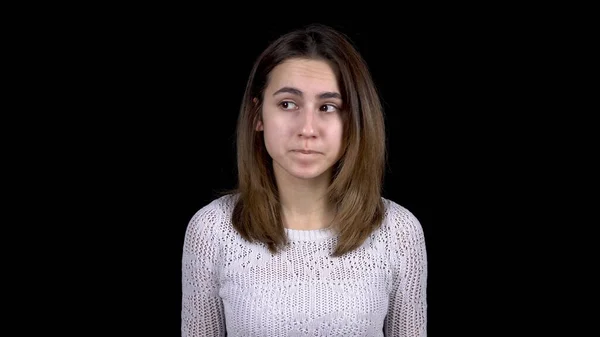 The young woman shows emotions of fear on her face. A woman shakes with fear and looks around on a black background. — Stock Photo, Image