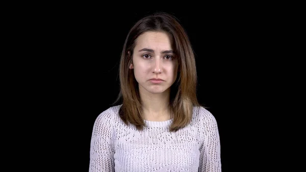 Μια νεαρή γυναίκα δείχνει συναισθήματα θλίψης στο πρόσωπό της. Η γυναίκα είναι λυπημένη σε μαύρο φόντο.. — Φωτογραφία Αρχείου