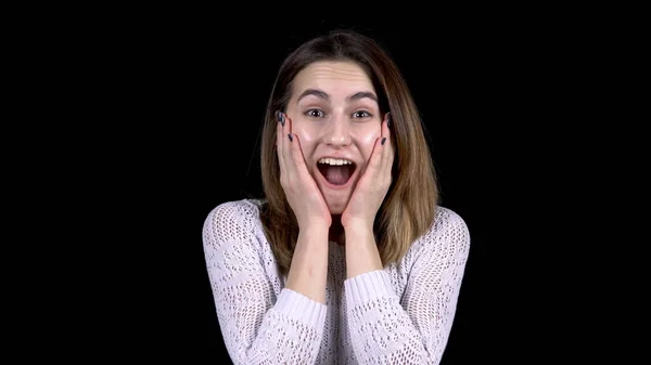 The young woman shows emotions of surprise on her face. Woman is surprised opening her mouth on a black background. — Stock Photo, Image