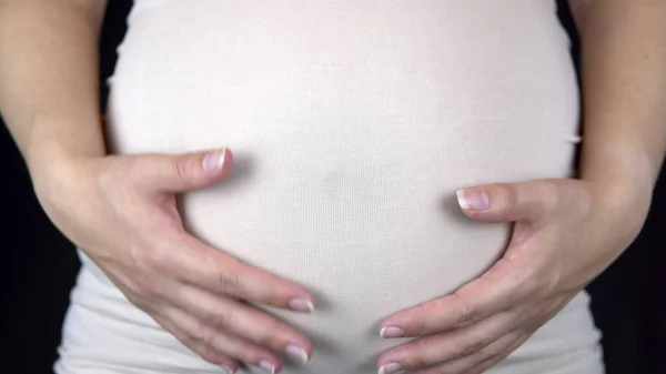 怀孕的女人用手抚摸着她的大肚子。穿着轻便T恤的女人 — 图库照片