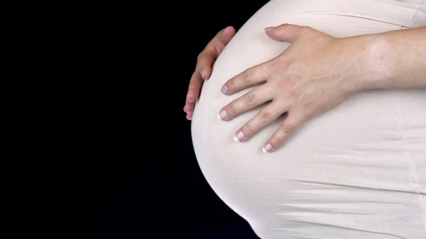 怀孕的女人用手抚摸着她的大肚子。穿着轻便T恤的女人 — 图库照片