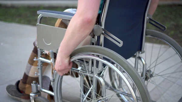 Jovem numa cadeira de rodas. Um homem monta em uma cadeira de rodas mão close-up. Transporte especial para deficientes . — Fotografia de Stock