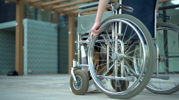 Uma jovem numa cadeira de rodas. Uma menina monta em uma cadeira de rodas mão close-up. Transporte especial para deficientes . — Fotografia de Stock