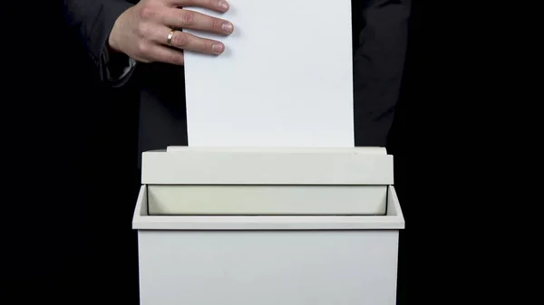 Shredder destroys documents. Businessman in a suit puts a sheet of paper into a paper shredder — ストック写真