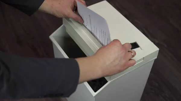 Shredder belgeleri yok ediyor. Takım elbiseli bir işadamı kağıt öğütücüsüne kağıt koyuyor.