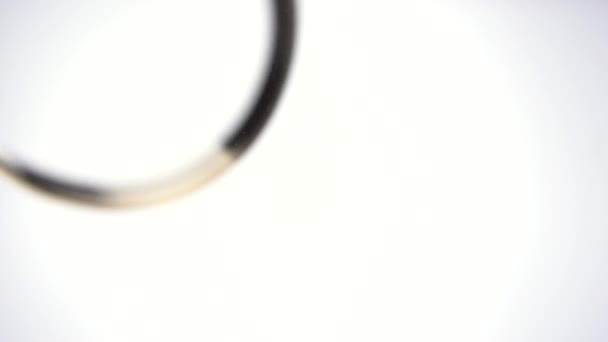 Ein Goldring fällt auf Glas auf einem strahlend weißen Hintergrund. Nahaufnahme des Rings von unten. Zeitlupe 100 fps. — Stockvideo