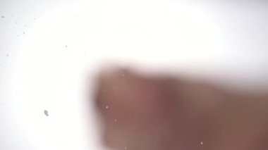 Tuz bardağın üstüne parlak beyaz bir arka plana düşer. Tuzun makro görüntüsü. Yavaş çekim 100 fps