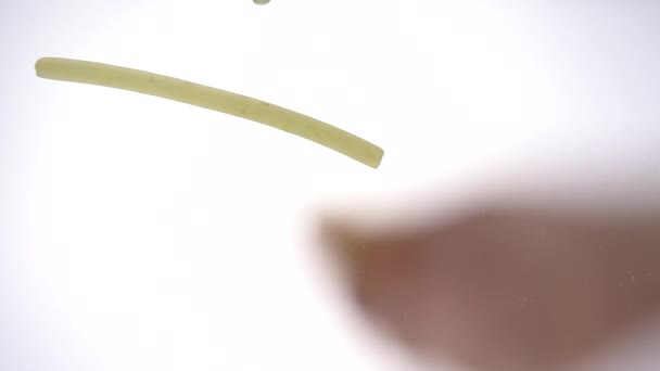 ヴェルミチェッリは明るい白い背景でガラスの上に落ちます。以下から麺のマクロビュー。スローモーション100 fps — ストック動画