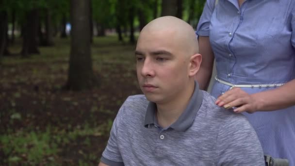 Une femme pose sa main sur l'épaule d'un jeune homme atteint d'un cancer pour le soutenir. L'homme pose sa main sur la main des femmes. Perte de cheveux due à la chimiothérapie. — Video